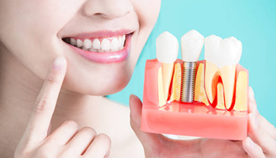 woman holding up a dental implant model and showing her teeth